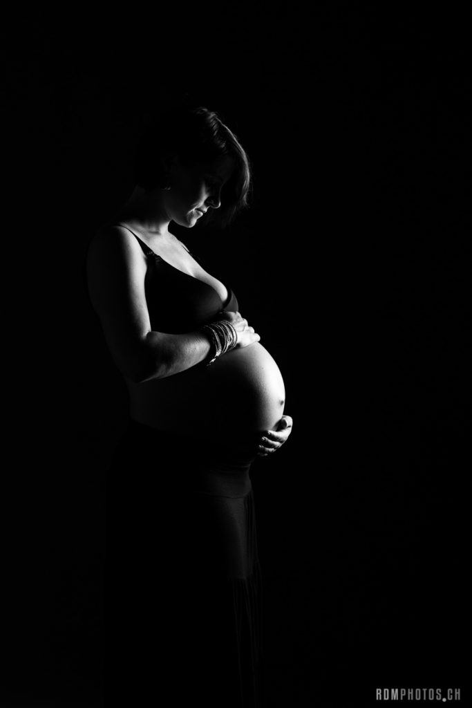 photographe de grossesse professionnel à genève. Femme enceinte photo en studio sur fond noir